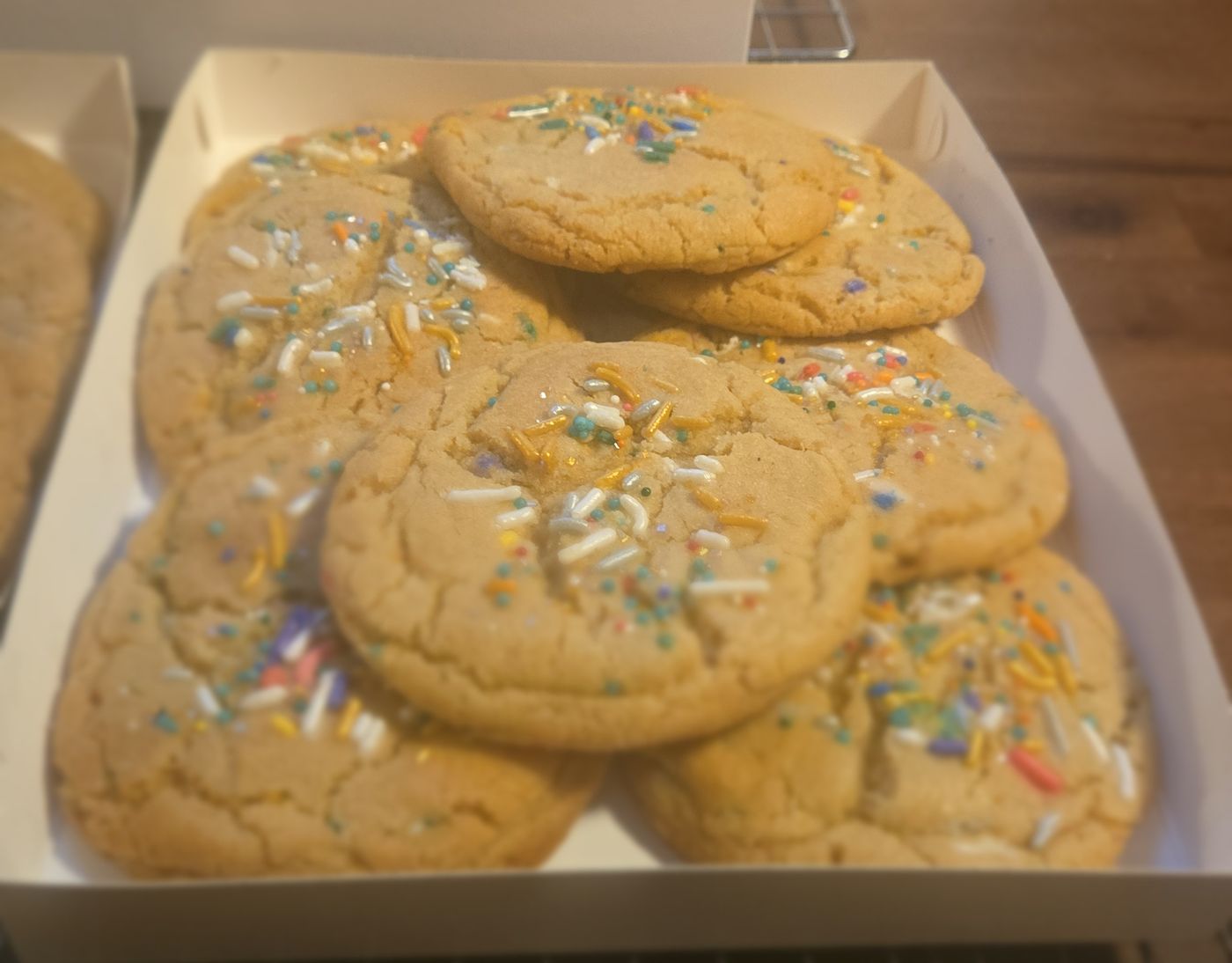 A box of soft sugar cookies topped with rainbow sprinkles